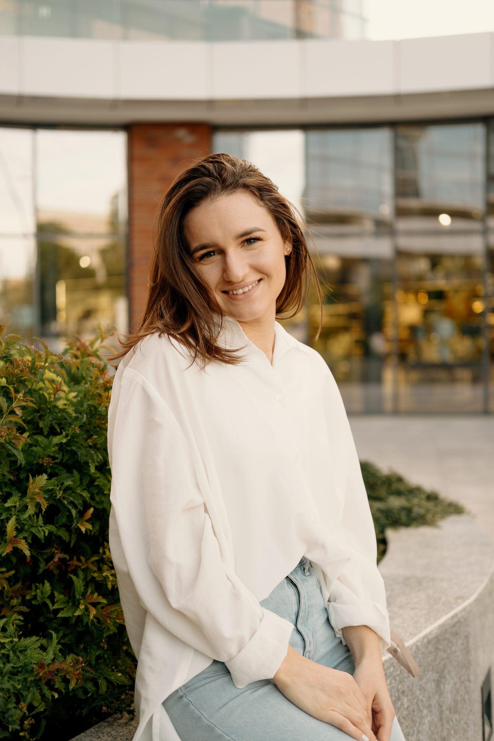 Urban portrait of a smiling at the camera girl standing outdoors after work.